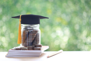 graduate cap on glass full of coins