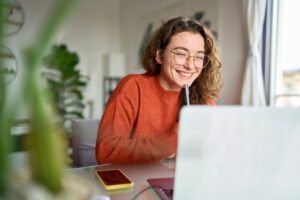 happy female student on laptop at home